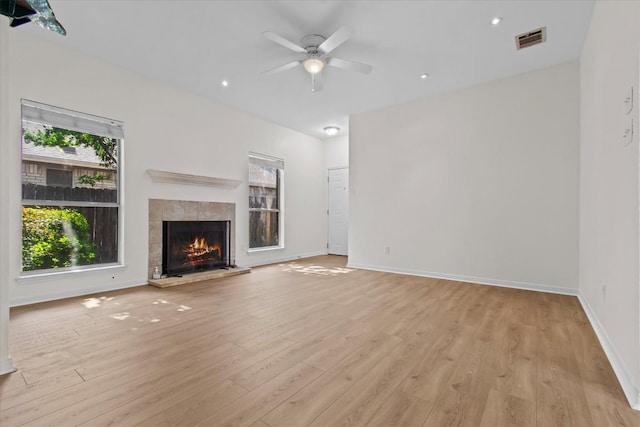 unfurnished living room with ceiling fan, light wood-type flooring, and a tile fireplace