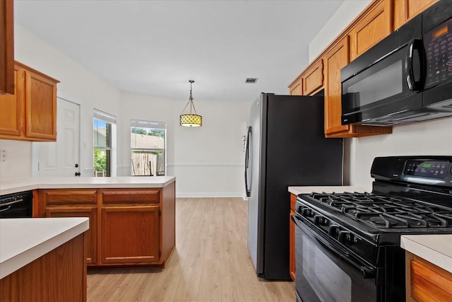 kitchen featuring black appliances, decorative light fixtures, kitchen peninsula, and light hardwood / wood-style flooring