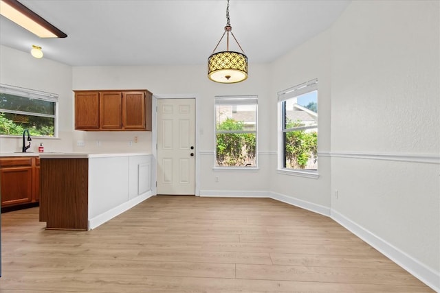 kitchen featuring sink, hanging light fixtures, and light hardwood / wood-style flooring