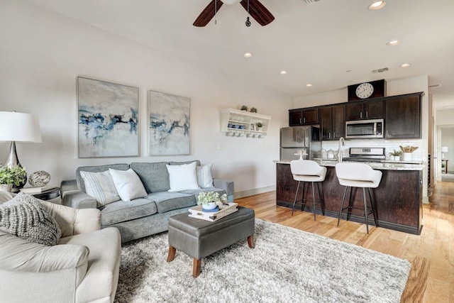 living room featuring ceiling fan and light hardwood / wood-style floors