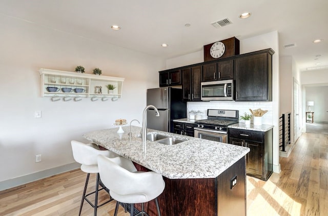 kitchen with stainless steel appliances, light hardwood / wood-style flooring, a kitchen island with sink, and sink