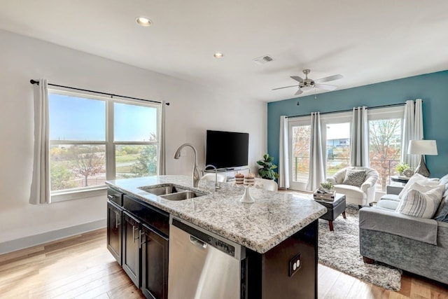 kitchen with a wealth of natural light, a kitchen island with sink, dishwasher, and sink