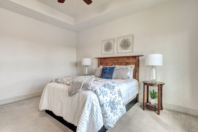 carpeted bedroom with a tray ceiling and ceiling fan