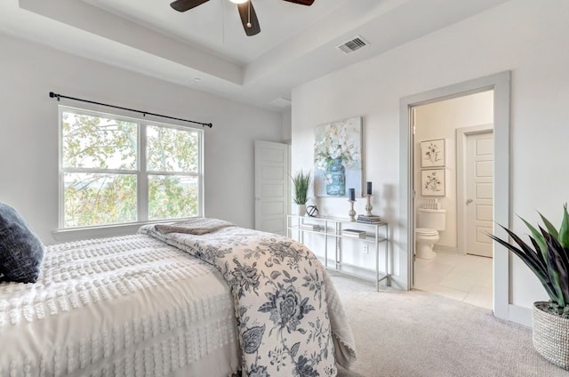 carpeted bedroom featuring ceiling fan, a raised ceiling, and connected bathroom