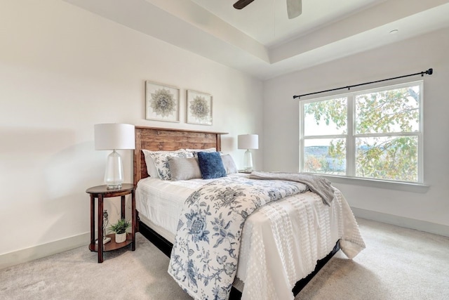 bedroom featuring a raised ceiling, ceiling fan, and light colored carpet