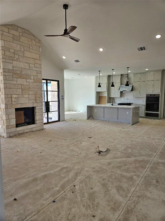 unfurnished living room with a fireplace, ceiling fan, lofted ceiling, and sink