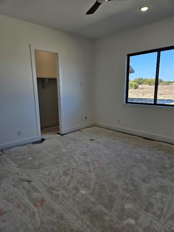 unfurnished bedroom with ceiling fan, a walk in closet, and a closet