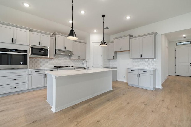 kitchen with a center island with sink, decorative light fixtures, sink, and stainless steel appliances