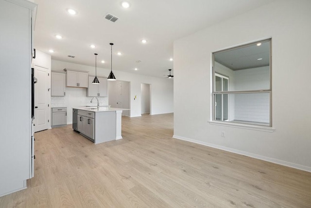 kitchen featuring pendant lighting, a center island with sink, sink, ceiling fan, and light hardwood / wood-style floors