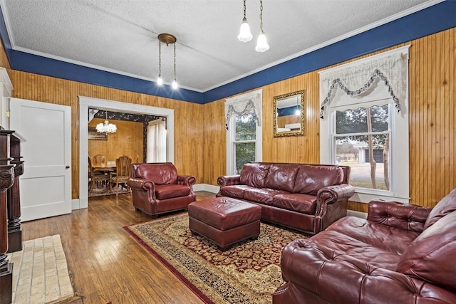 living room featuring hardwood / wood-style floors, a textured ceiling, ornamental molding, and wood walls