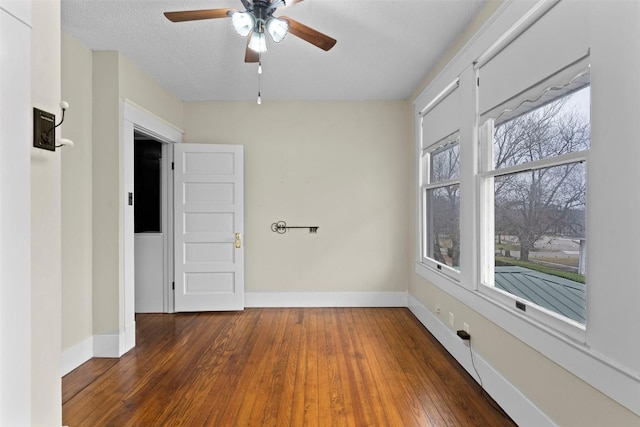 empty room featuring a textured ceiling, ceiling fan, and dark wood-type flooring