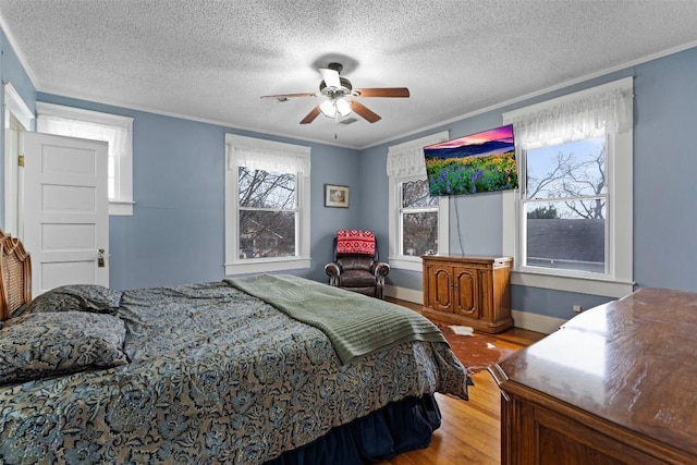 bedroom with wood-type flooring, a textured ceiling, ceiling fan, and crown molding