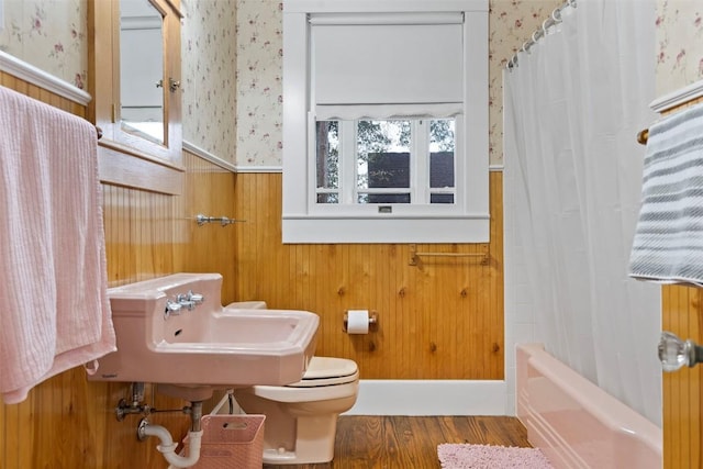 full bathroom with shower / tub combo, sink, hardwood / wood-style flooring, toilet, and wood walls