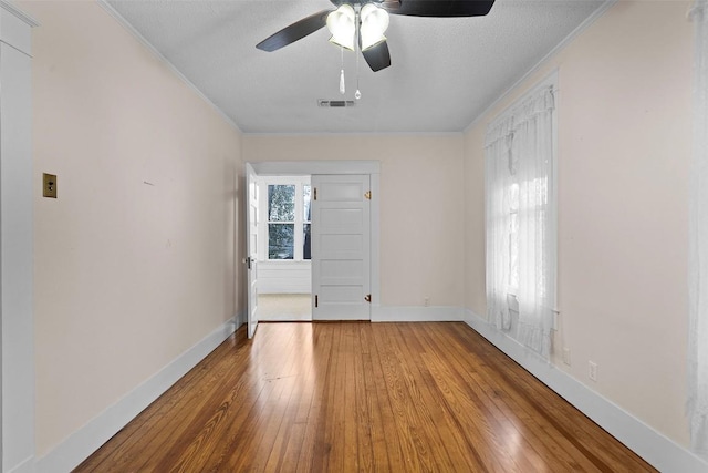 empty room featuring ceiling fan, crown molding, a textured ceiling, and hardwood / wood-style flooring