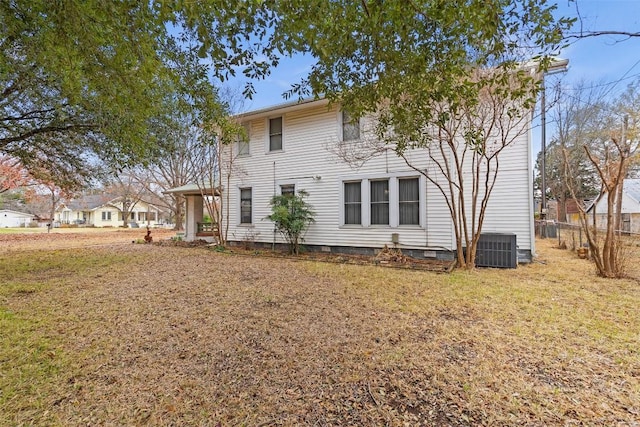 rear view of house with cooling unit and a yard