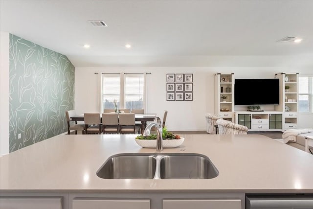 kitchen featuring a kitchen island with sink, sink, and dishwasher