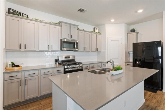 kitchen featuring sink, an island with sink, light hardwood / wood-style flooring, and appliances with stainless steel finishes