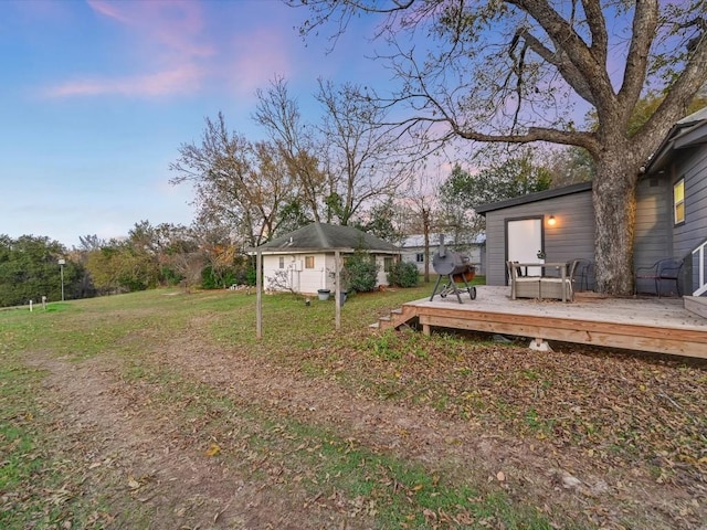 yard at dusk featuring a wooden deck and an outdoor structure