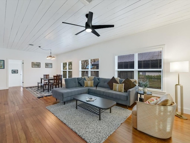 living area featuring ceiling fan with notable chandelier, hardwood / wood-style flooring, and wood ceiling