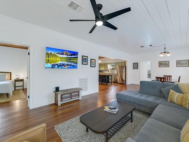 living area featuring wood finished floors, baseboards, a ceiling fan, and visible vents