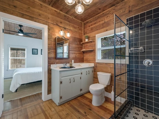 bathroom with a tile shower, wooden walls, wood-type flooring, and a wealth of natural light