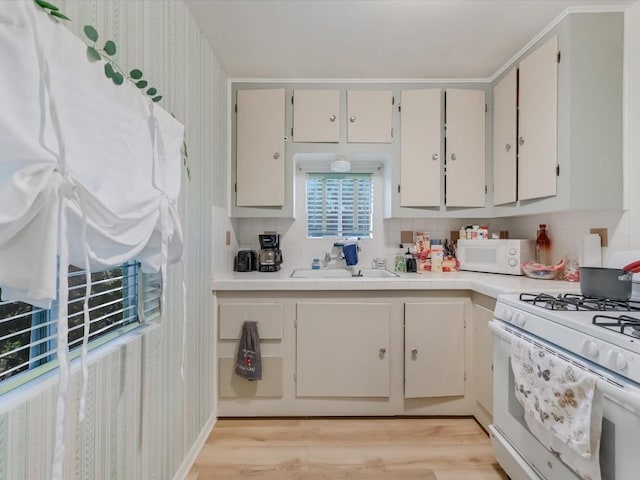 kitchen with white appliances, sink, light hardwood / wood-style flooring, tasteful backsplash, and white cabinetry