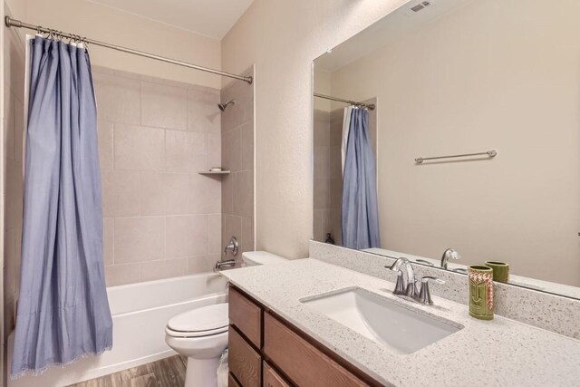 full bathroom with toilet, wood-type flooring, vanity, and shower / tub combo with curtain