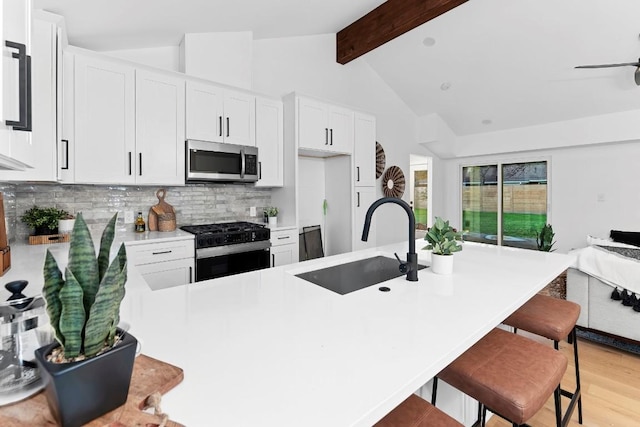 kitchen featuring white cabinets, sink, tasteful backsplash, light hardwood / wood-style floors, and stainless steel appliances