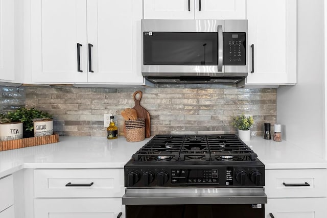 kitchen featuring white cabinets, black range with gas stovetop, and backsplash