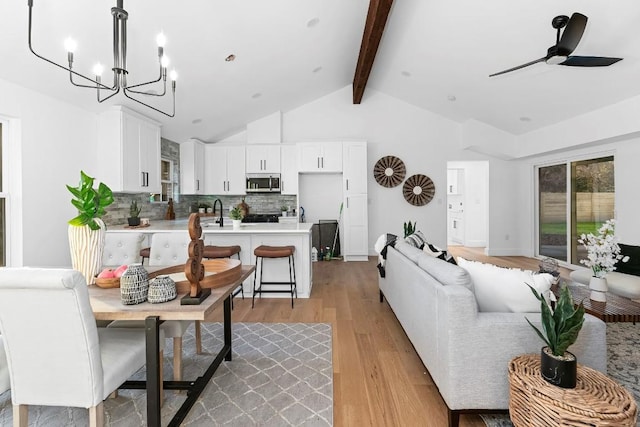 interior space with vaulted ceiling with beams, ceiling fan with notable chandelier, light hardwood / wood-style floors, and sink