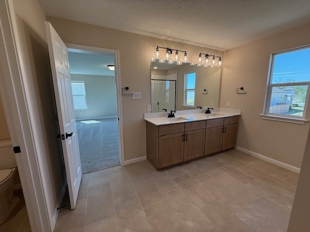 128 Alistair Dr, Georgetown, TX 78633 - full bathroom featuring toilet, double vanity, a shower stall, healthy amount of natural light, and a textured ceiling