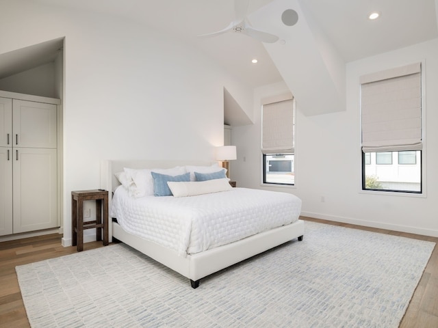 bedroom with ceiling fan, light wood-type flooring, and vaulted ceiling