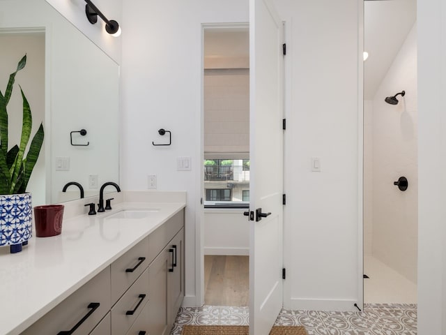 bathroom with hardwood / wood-style flooring, vanity, and a tile shower