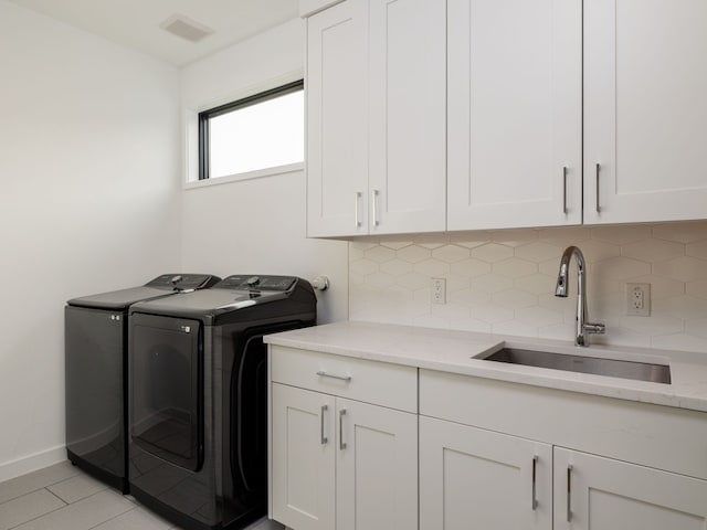 laundry room with cabinets, light tile patterned floors, sink, and washing machine and dryer