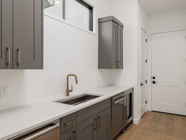 kitchen featuring gray cabinets, dishwasher, light hardwood / wood-style floors, and sink