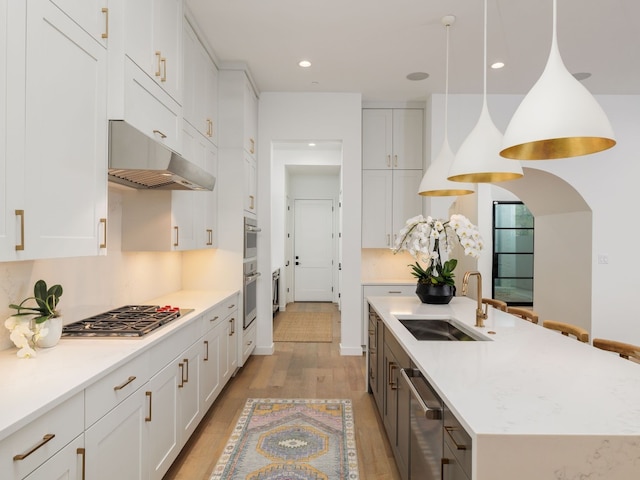 kitchen featuring white cabinets, sink, stainless steel appliances, and hanging light fixtures