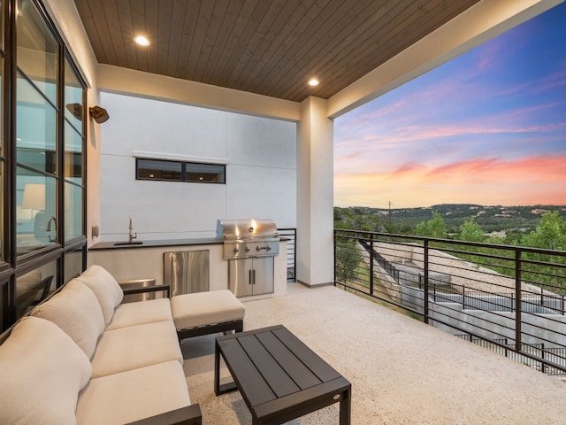 patio terrace at dusk with outdoor lounge area, area for grilling, a balcony, and sink