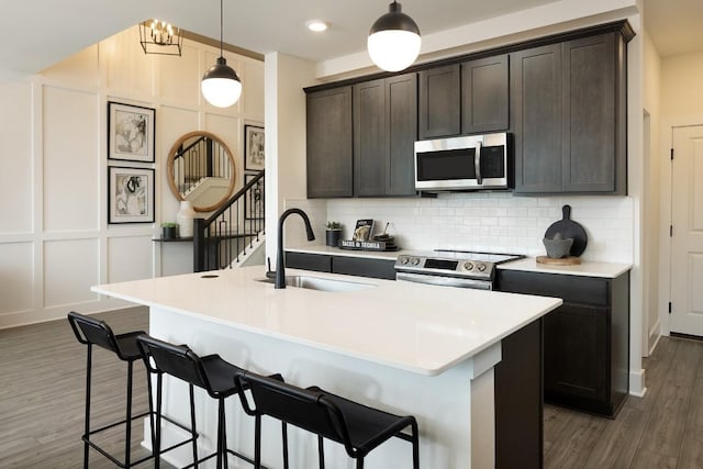 kitchen featuring a center island with sink, dark hardwood / wood-style floors, sink, and appliances with stainless steel finishes