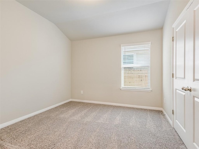 spare room featuring carpet and vaulted ceiling