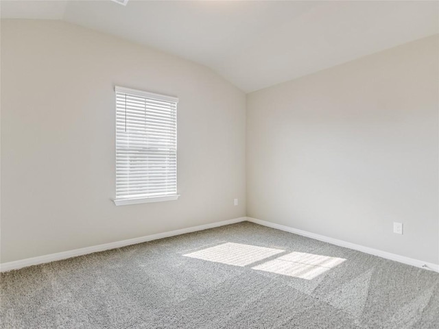 carpeted spare room featuring lofted ceiling