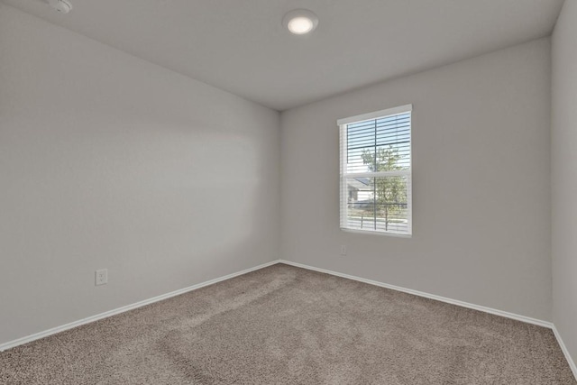 carpeted spare room featuring baseboards