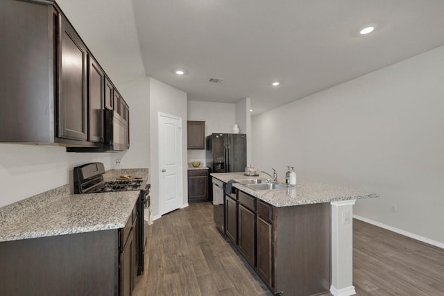kitchen with a sink, dark brown cabinetry, black appliances, and dark wood-style flooring