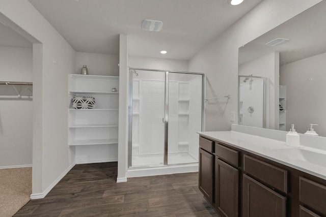 bathroom with vanity, wood finished floors, a spacious closet, and a shower stall