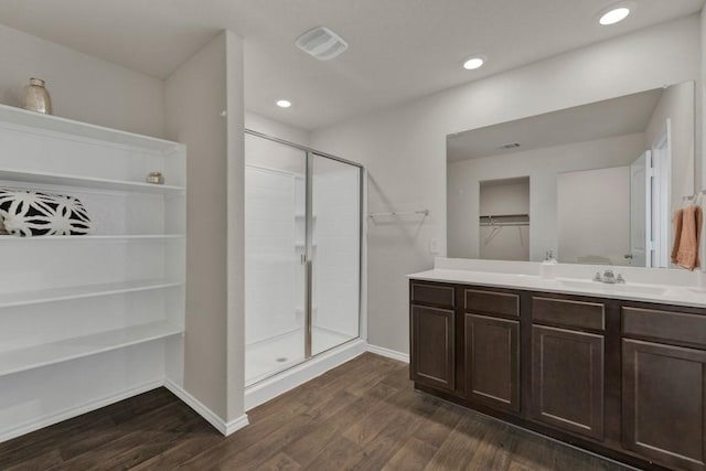 bathroom featuring a walk in closet, baseboards, a shower stall, and wood finished floors