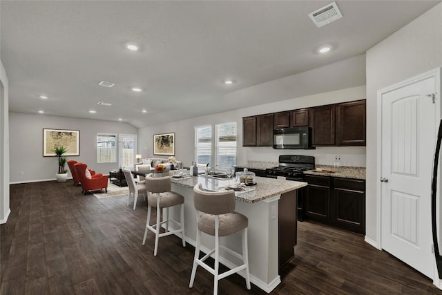 kitchen with plenty of natural light, open floor plan, a breakfast bar area, and black appliances