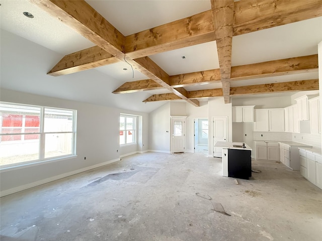 unfurnished living room with lofted ceiling with beams