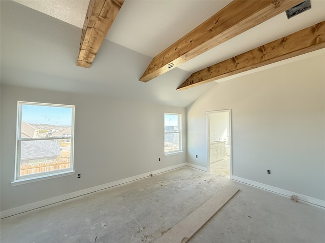 spare room with a wealth of natural light and vaulted ceiling with beams