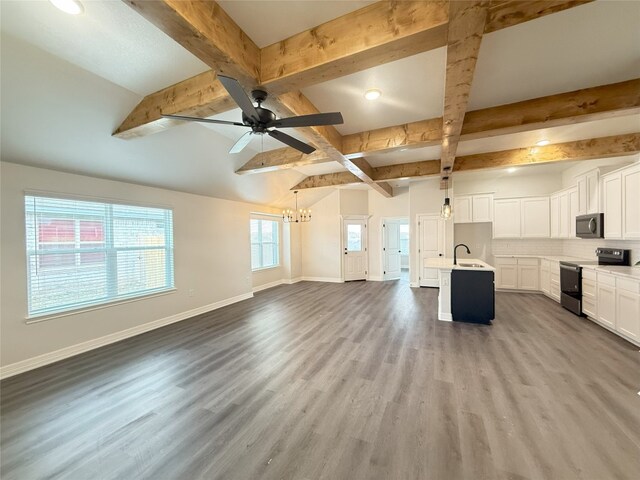 unfurnished living room with a sink, baseboards, beamed ceiling, and ceiling fan with notable chandelier