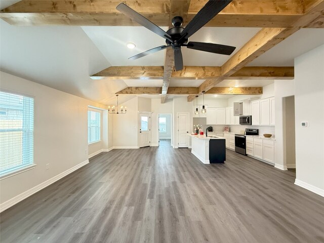 kitchen featuring beamed ceiling, stainless steel appliances, open floor plan, and ceiling fan with notable chandelier