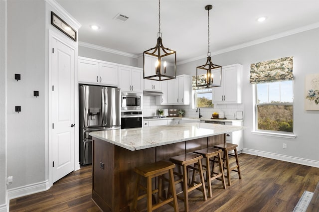 kitchen with dark hardwood / wood-style floors, white cabinets, appliances with stainless steel finishes, and a center island